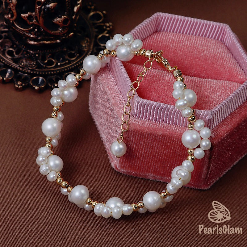 Pearl bracelet with gold accents on a brown surface with a pink velvet box.