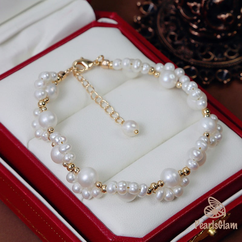 Pearl bracelet with gold accents on a red jewelry box, featuring the brand 'PearlsGlam'.