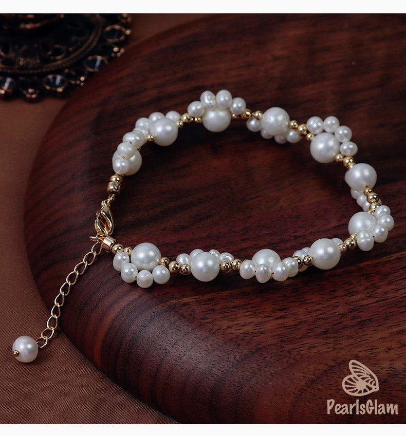 Pearl bracelet with gold chain on a wooden surface, brand 'PearlsGlam' visible
