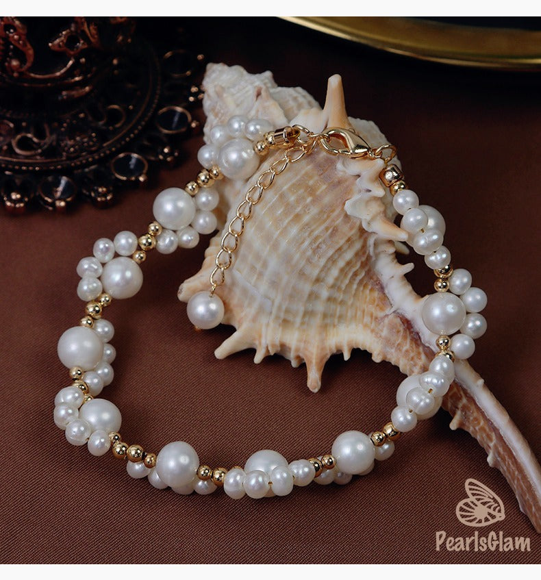 Pearl bracelet with gold accents on a shell with 'PearlsGlam' branding.