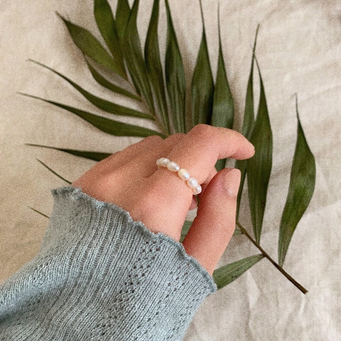 Real-person demonstration of the Freshwater Pearl Stretch Ring with green bakground