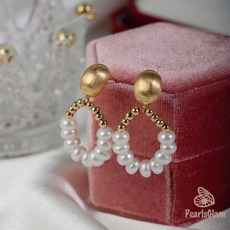 Pearl and gold hoop earrings on a pink jewelry box with 'PearlsGlam' branding.